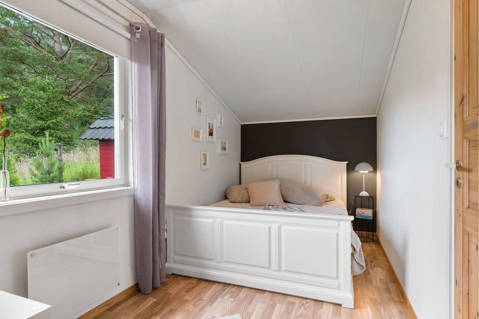 Bright and cozy minimalist bedroom featuring a large window with a view of greenery.